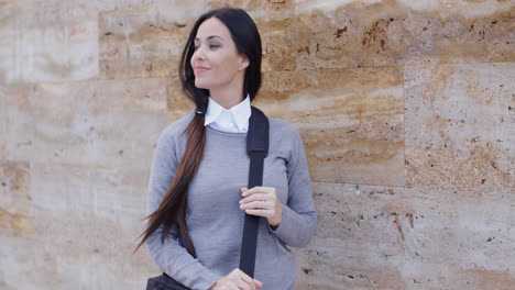 Grinning-woman-in-sweater-near-wall-looking-over