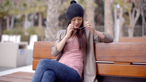 Mujer-Joven-De-Moda-Relajándose-En-Un-Banco-Del-Parque