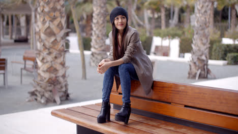 Fashionable-young-woman-sitting-waiting-on-a-bench