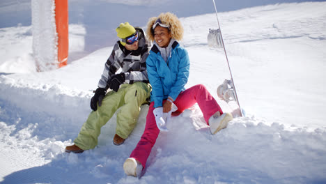 Feliz-Pareja-Joven-Relajándose-En-Una-Plataforma-De-Nieve