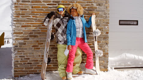 Pareja-Cercana-Posando-Con-Tablas-De-Snowboard-Contra-El-Garaje