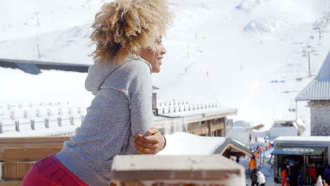 Smiling-woman-leaning-on-railing-at-ski-resort