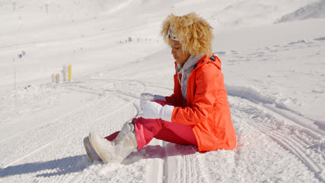 Mujer-En-Traje-De-Nieve-Naranja-Sentada-En-La-Pista-De-Esquí