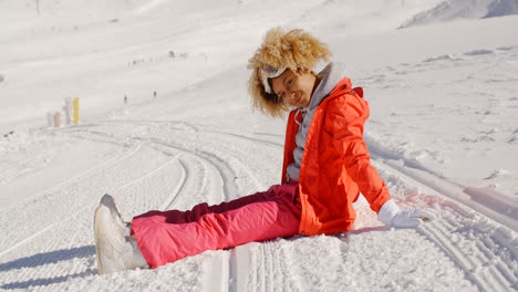 Frau-Im-Orangefarbenen-Schneeanzug-Sitzt-Auf-Der-Skipiste