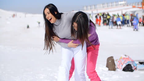 Zwei-Verspielte-Frauen-Tummeln-Sich-Im-Schnee