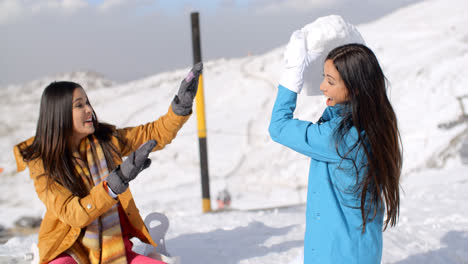 Two-young-female-friends-playing-in-the-snow