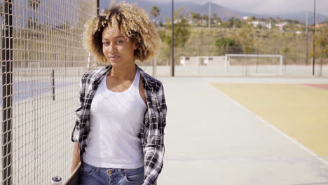 Mujer-Joven-Con-Patineta-Posa-Por-Cancha-De-Pelota