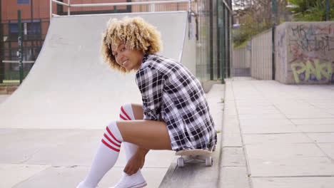 Junge-Frau-Sitzt-Auf-Ihrem-Skateboard-Auf-Der-Eisbahn