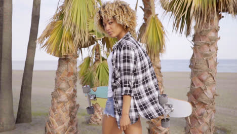 Young-woman-at-the-beach-with-her-skateboard