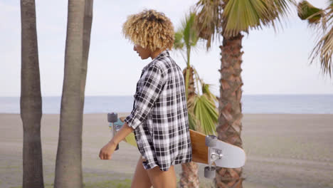 Young-woman-at-the-beach-with-her-skateboard