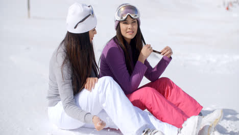 Dos-Amigas-Jóvenes-Relajándose-En-La-Nieve.