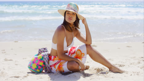 Pretty-young-woman-sitting-on-the-beach-sand