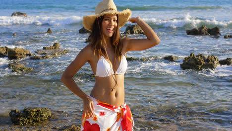 Laughing-young-woman-standing-on-a-rocky-seashore