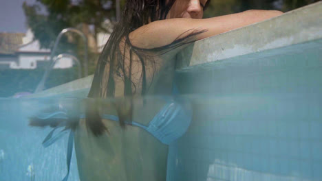 Underwater-view-of-woman-leaning-on-edge-of-pool