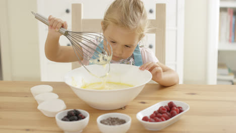 Mädchen-Betrachtet-Muffinteig-Mit-Schneebesen