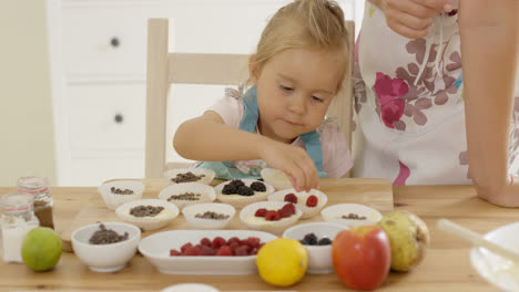 Kleines-Mädchen-Legt-Beeren-Auf-Muffins