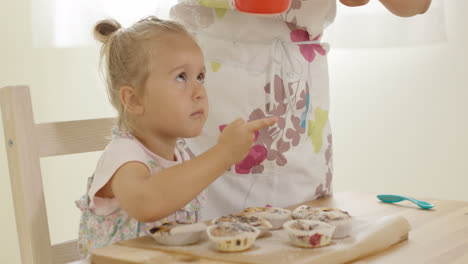 Child-interested-in-sugar-falling-on-baked-muffins