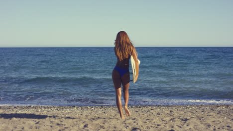 Sexy-Frau-Mit-Surfbrett-Zu-Fuß-Am-Strand