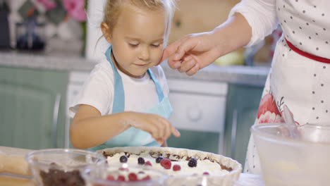 Lächelndes-Kleines-Mädchen,-Das-Beeren-Auf-Einen-Kuchen-Gibt