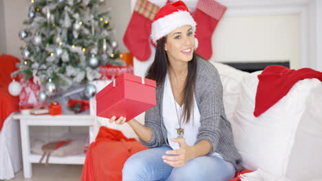 Mujer-Joven-Curiosa-Agitando-Un-Regalo-De-Navidad