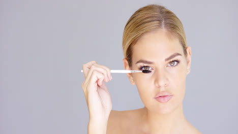 Pretty-blond-woman-applying-mascara