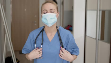 Medical-practitioner-in-mask-adjusting-stethoscope