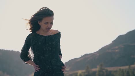 short-haired-girl-in-black-dress-poses-against-mountains