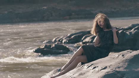 fair-haired-girl-fixes-tight-dress-on-huge-rock-slow-motion