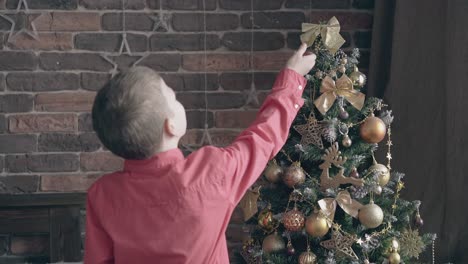 Un-Niño-Rubio-Reorganiza-Las-Decoraciones-Del-Arco-En-El-árbol-De-Navidad