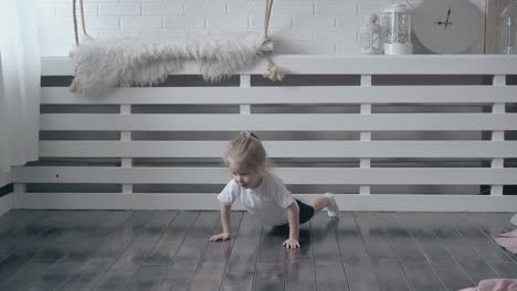 cute-toddler-pushes-up-on-wooden-floor-against-wall-shelf