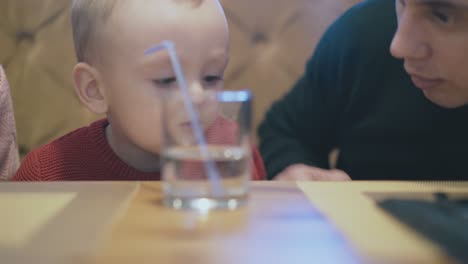 handsome-man-talks-to-kid-with-glass-of-water-on-foreground