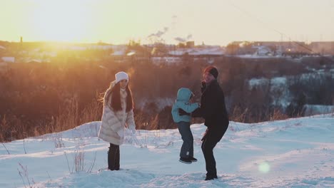 family-entertains-on-white-snow-ground-against-blurry-roofs