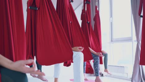 Eine-Erfahrene-Fly-Yoga-Gruppe-Sitzt-In-Roten-Hängematten-Und-Entspannt-Sich