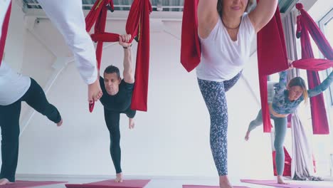 concentrated-man-and-ladies-practice-anti-gravity-yoga