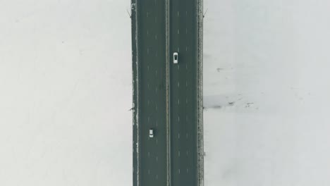 Breite-Autobahnbrücke-Mit-Fahrenden-Fahrzeugen-über-Dem-Zugefrorenen-Fluss