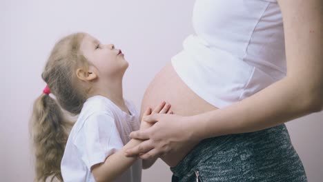 cute-child-talks-to-pregnant-mother-hugging-large-belly