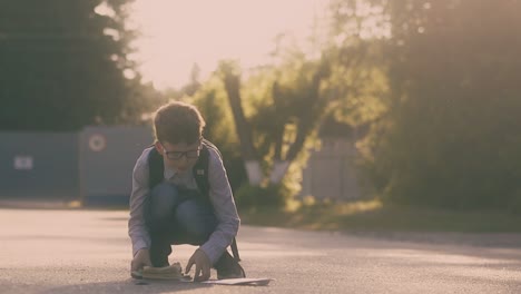 boy-in-shirt-and-jeans-gathers-books-and-sheets-on-asphalt