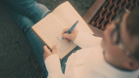 young-guy-in-white-shirt-and-blue-jeans-draws-on-book-sheet