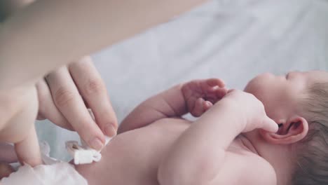 Säugling-Liegt-Auf-Dem-Bett-Und-Mutter-Desinfiziert-Die-Nabelschnur