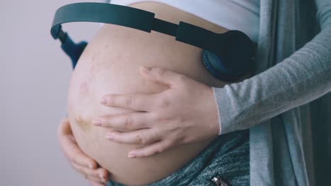 pregnant-lady-with-headphones-on-tummy-dances-in-room