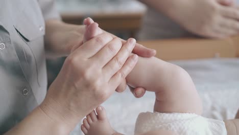 Die-Hände-Des-Kinderarztes-Halten-Das-Bein-Des-Neugeborenen-Jungen-Und-Reiben-Und-Massieren-Es