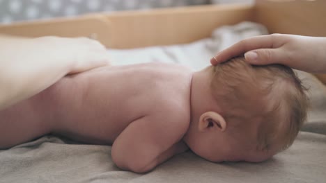 infant-boy-lies-on-stomach-and-nurse-practices-back-massage
