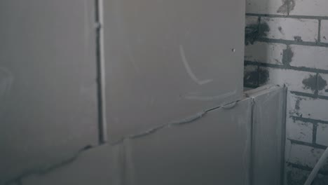 worker-puts-gypsum-plasterboard-on-grey-wall-construction