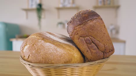 Frau-Serviert-Korb-Mit-Bio-Brot-Auf-Dem-Tisch-In-Der-Küche
