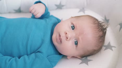 cute-baby-in-blue-bodysuit-rests-in-comfortable-cocoon