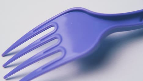 motion-along-violet-disposable-fork-on-white-background