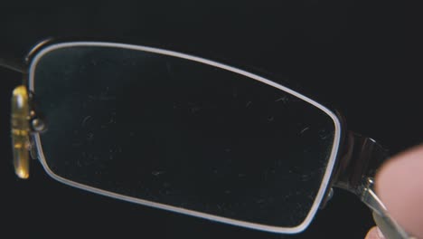 Person-Zeigt-Moderne-Schmutzige-Brillen-Auf-Schwarzem-Hintergrund