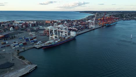Aerial-orbit-shot-showing-ship-docking-at-container-port-of-Fremantle-in-Perth-City-at-dusk