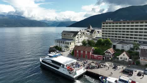 High-speed-catamaran-Vingtor-alongside-with-passengers-in-Balestrand-Sognefjord-Norway---Sunny-day-aerial-with-Kviknes-Hotel-and-Sognefjord-in-background