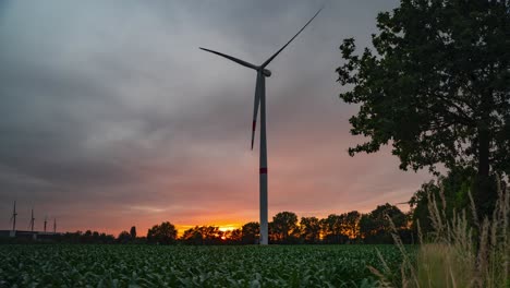 Lonely-wind-turbine-against-glowing-and-stormy-sunset-sky,-day-to-night-time-lapse